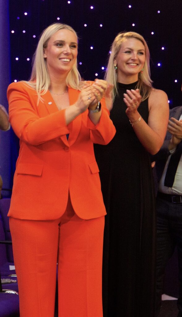 Two Rapport people clapping a colleague receiving an award at Rapport Excellence Awards.