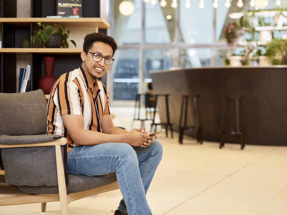 Man holding iPhone in a reception and looking at you.